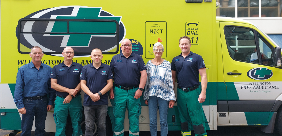 A group of people smile in front of an ambulance